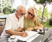 Insured Retirement Plan - Irp - A Senior Couple Sitting Together And Looking At A Laptop And Notebook.